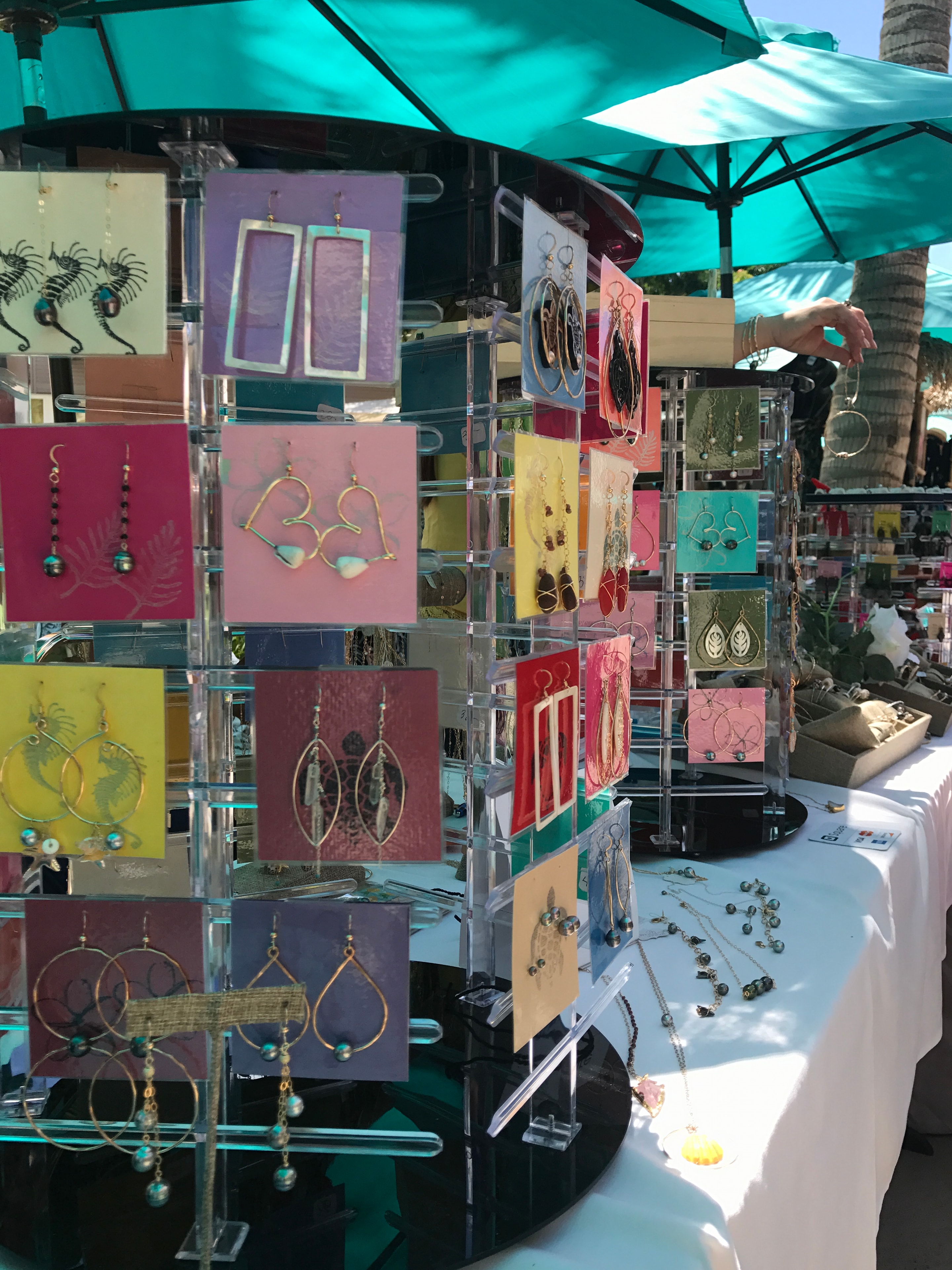 Handmade wire earrings displayed on colorful cards at jewelry booth