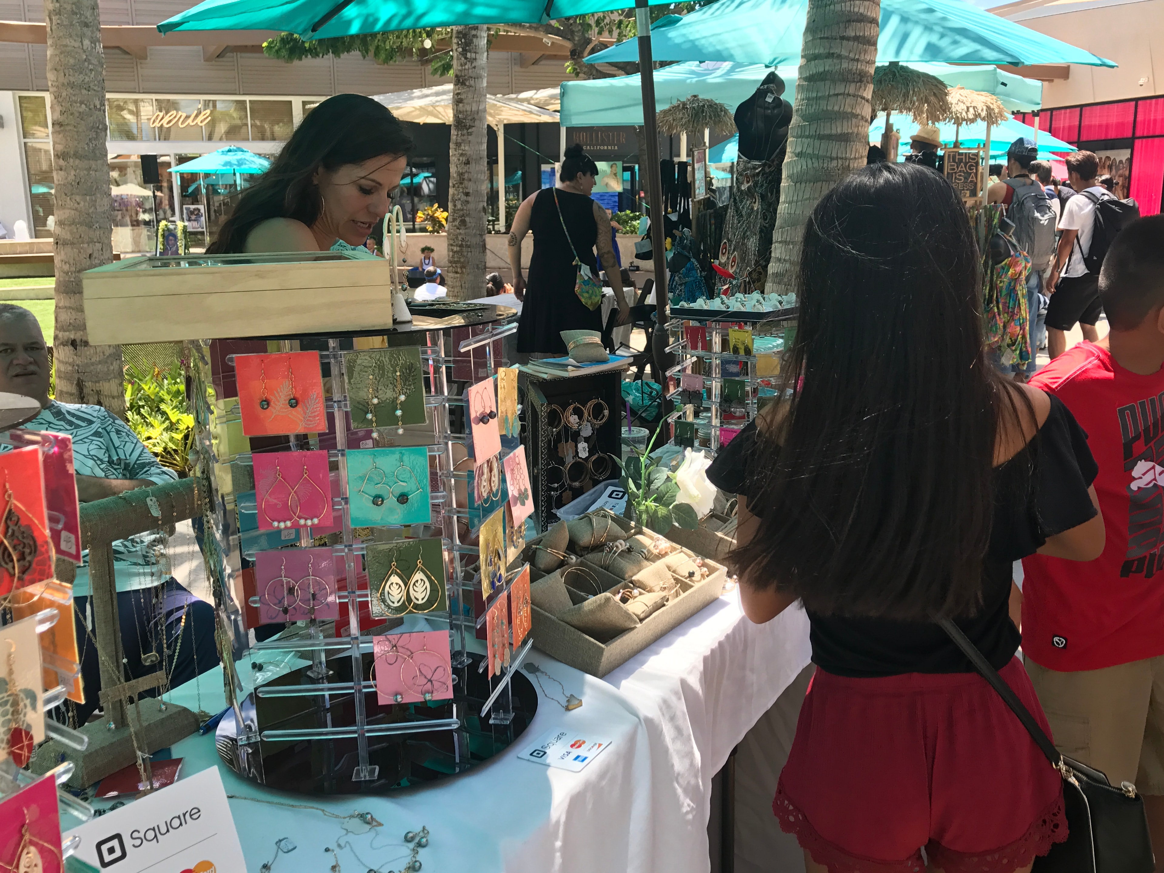 Jewelry vendor with customer browsing earrings and bracelets
