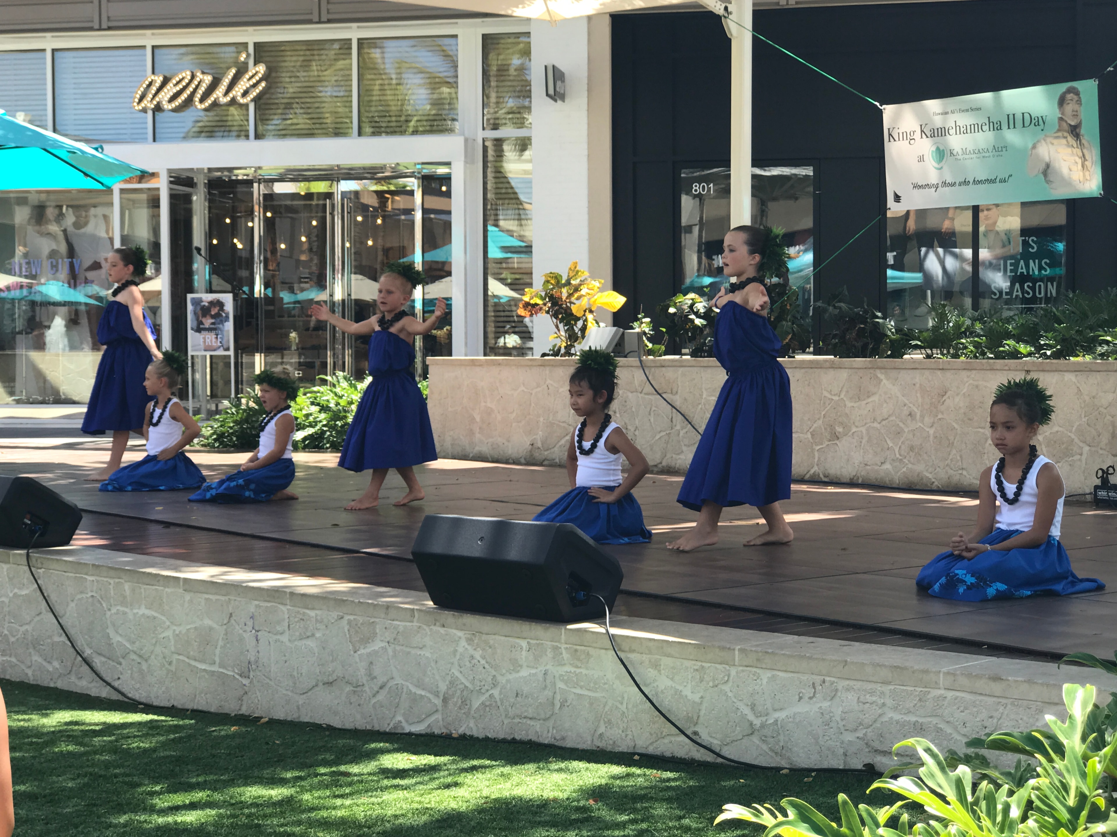 Children in blue hula skirts performing on outdoor stage at King Kamehameha II Day