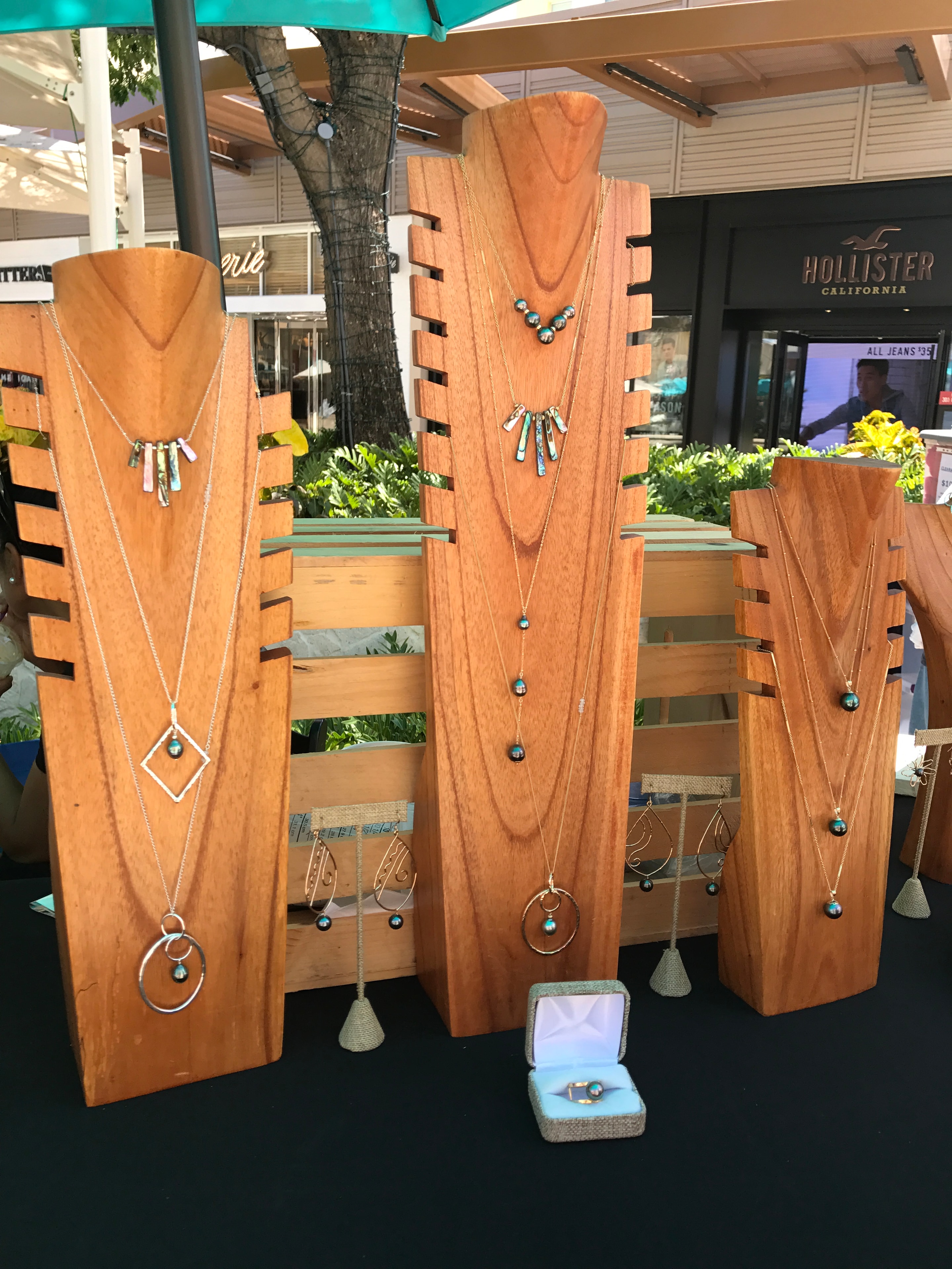 Handcrafted necklaces and earrings displayed on koa wood boards