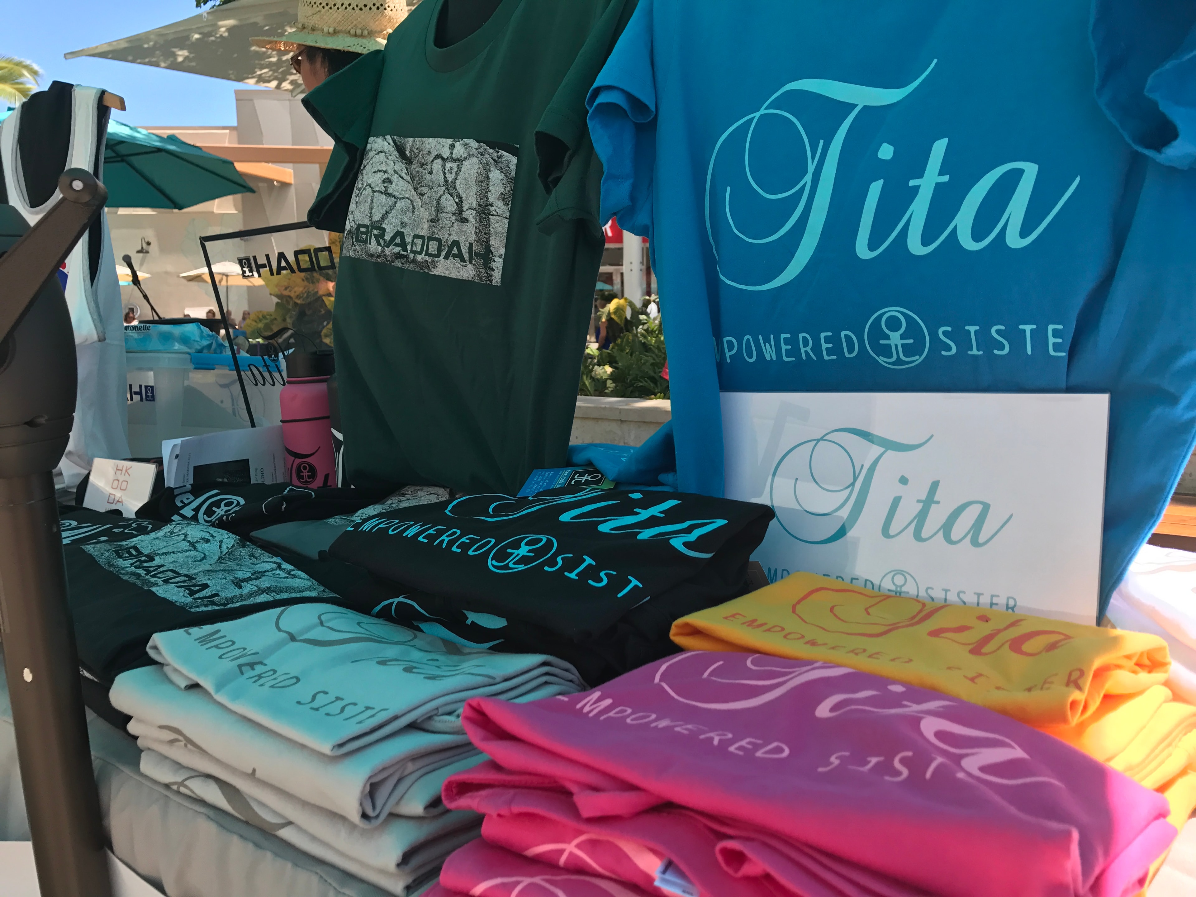 Tita Powered Sister branded t-shirts in multiple colors at vendor booth