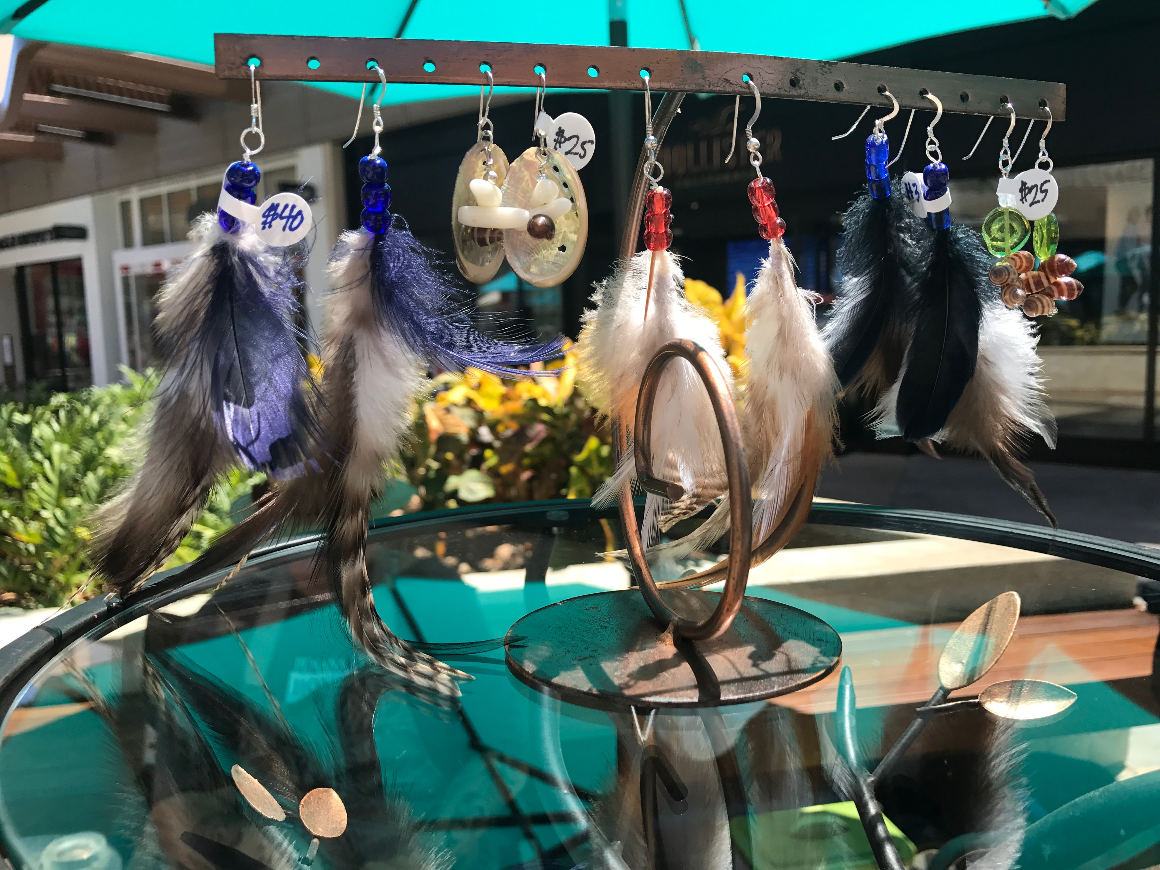 Feather and bead earrings hanging on copper display stand