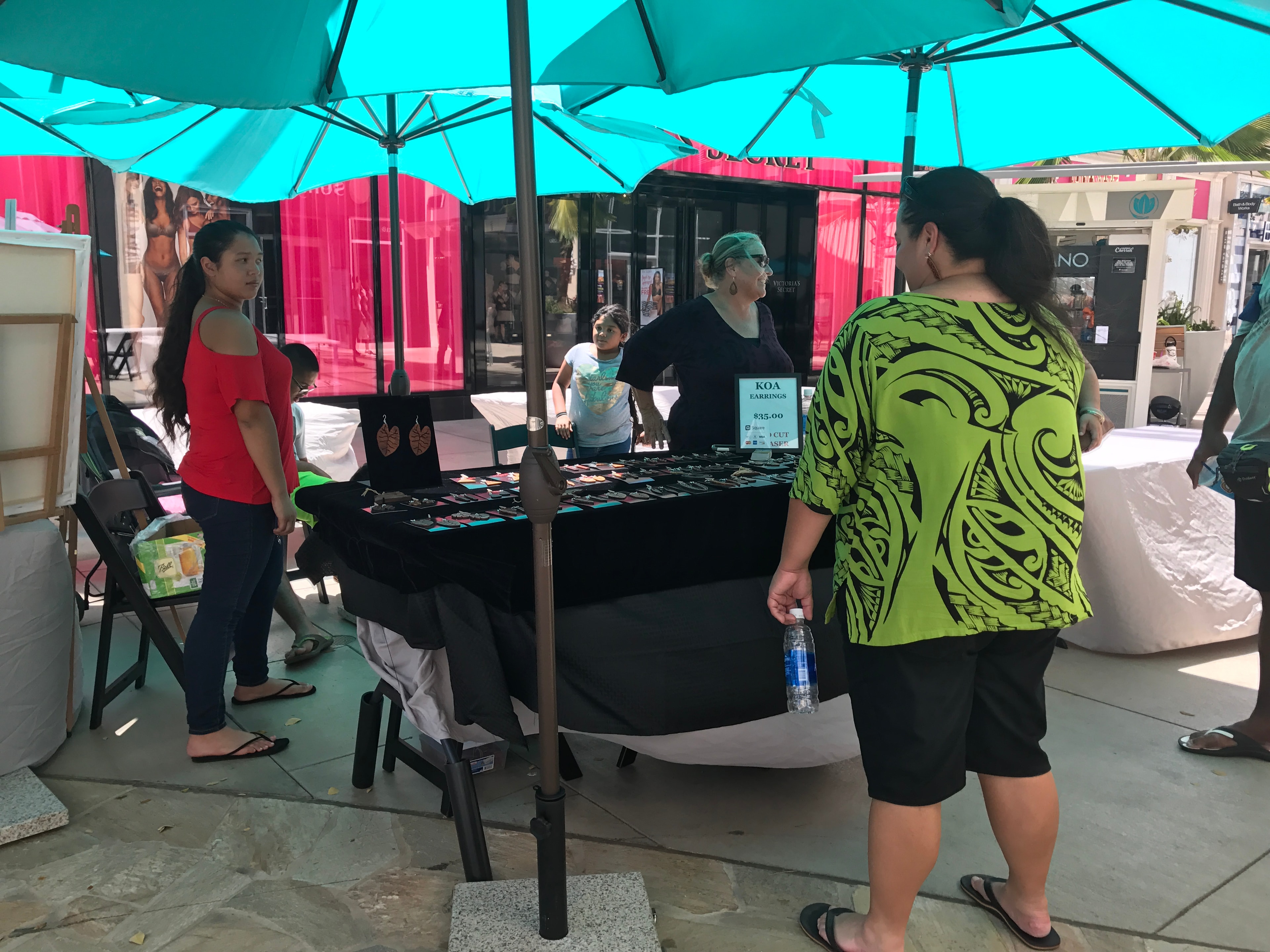 Outdoor market with teal umbrellas and colorful vendor booths