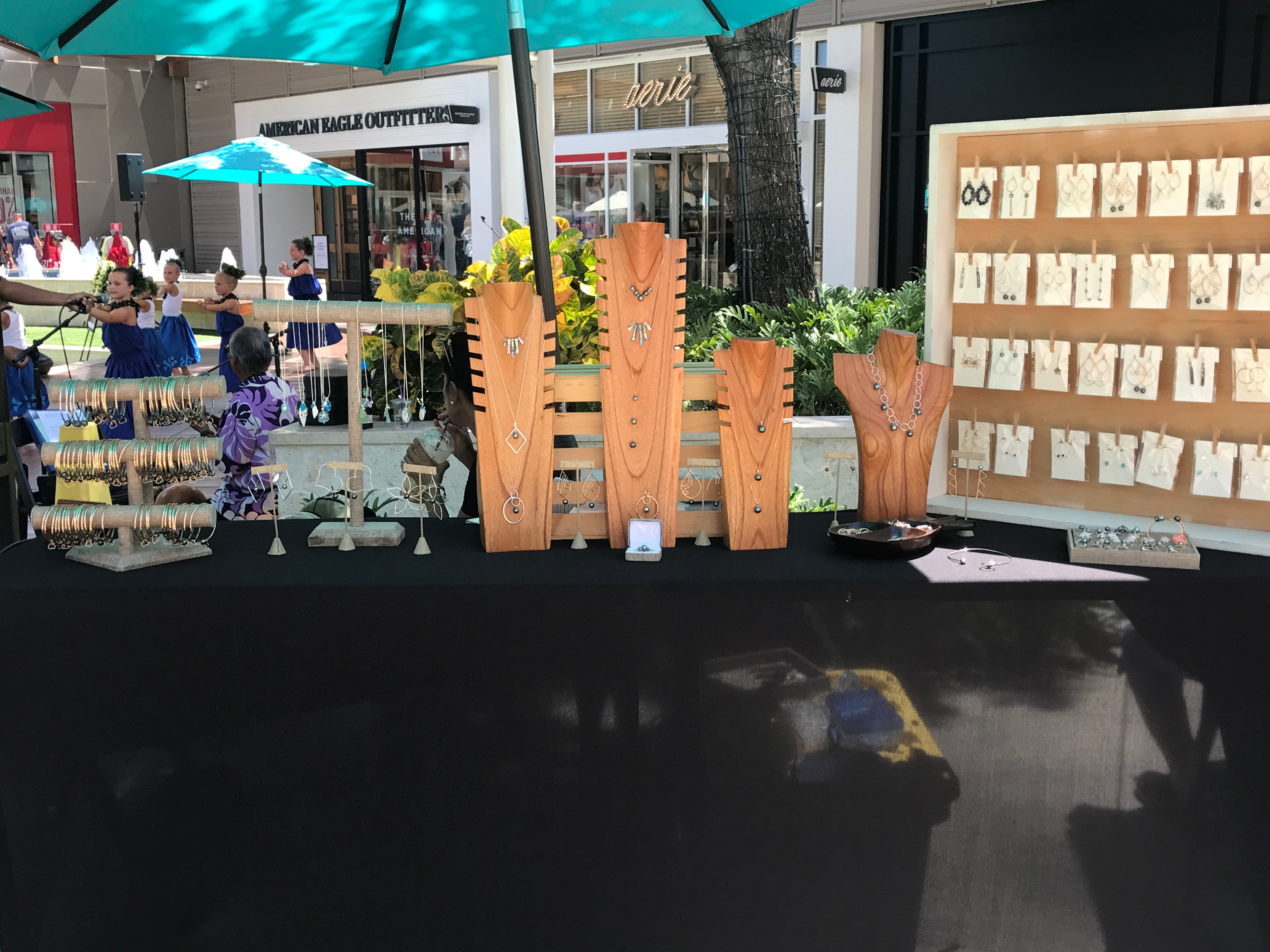 Jewelry vendor booth with wooden display stands, necklaces, and bracelets