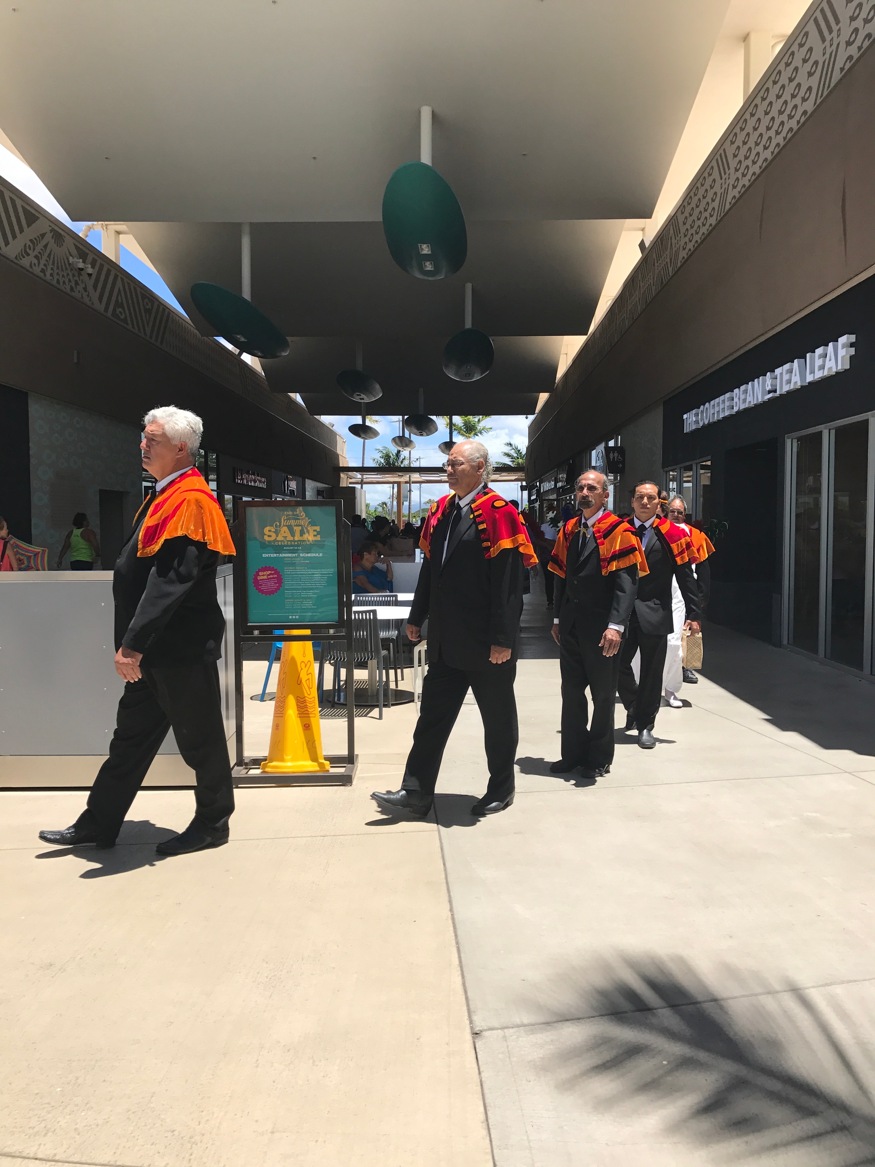 Men in orange and black royal regalia at Ka Makana Aliʻi