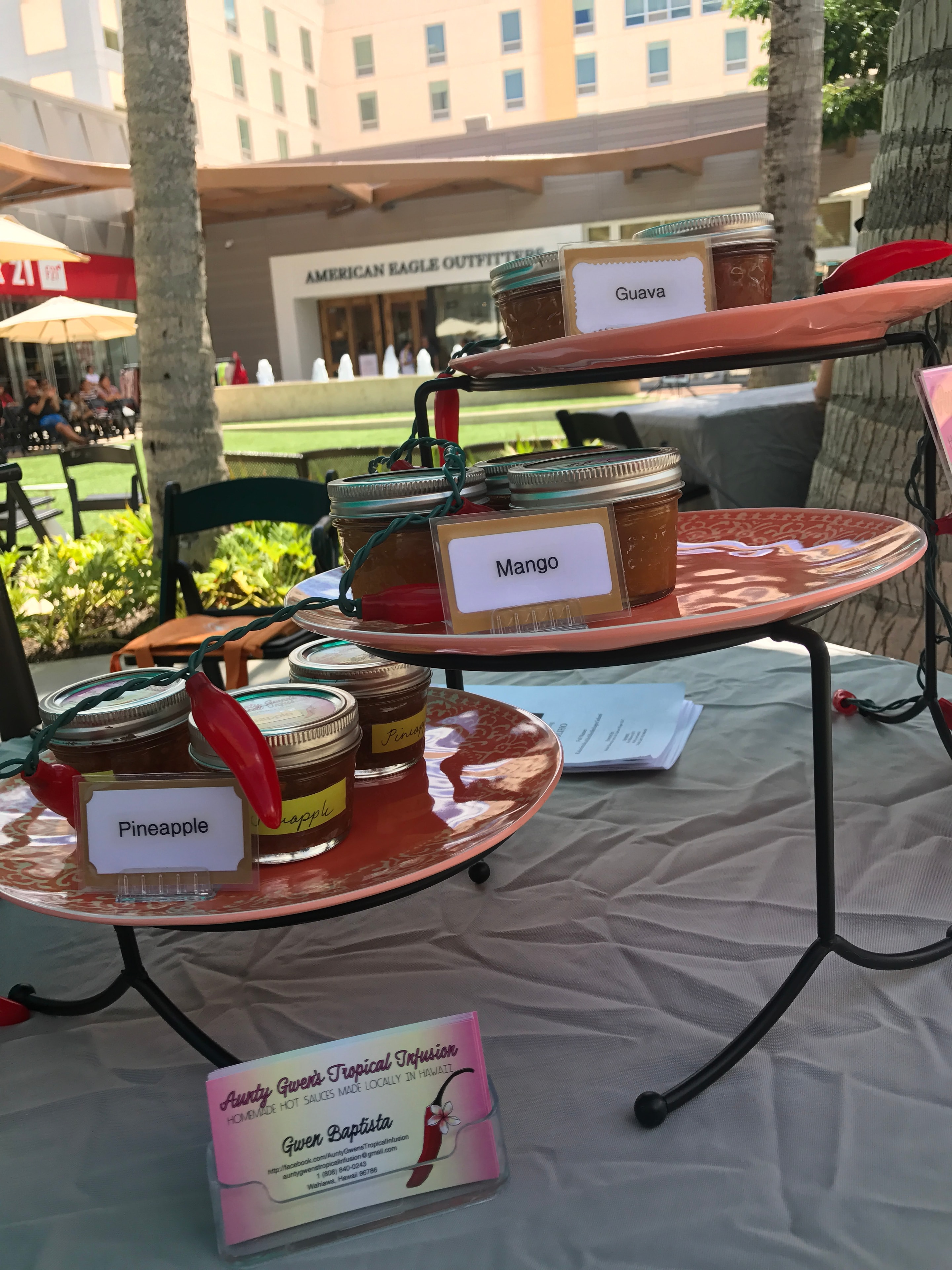 Aunty Gwen's Tropical Infusion guava, mango, and pineapple hot sauce jars on tiered display