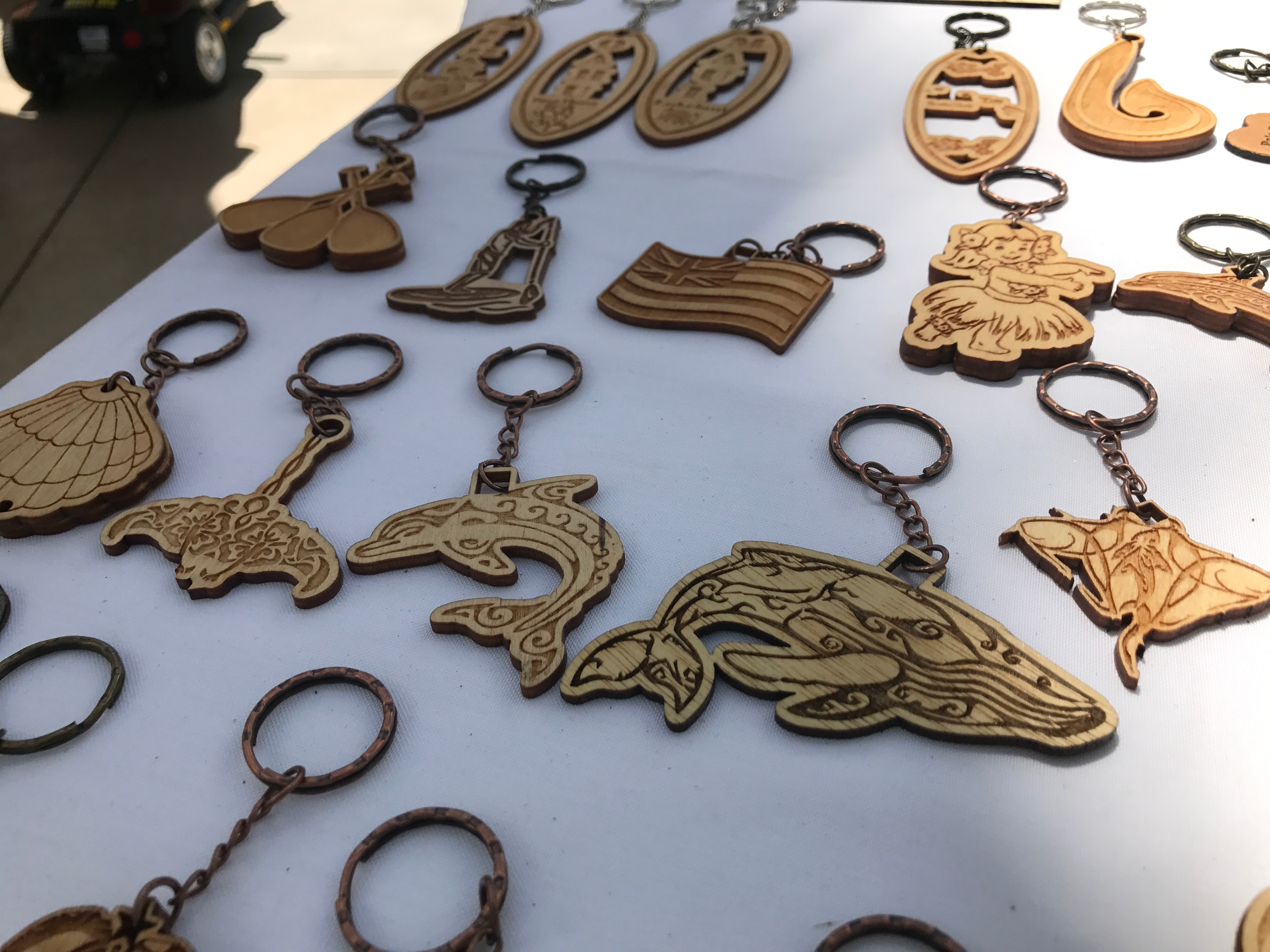 Engraved wooden keychains in dolphin, whale, manta ray, and Hawaiian motif shapes