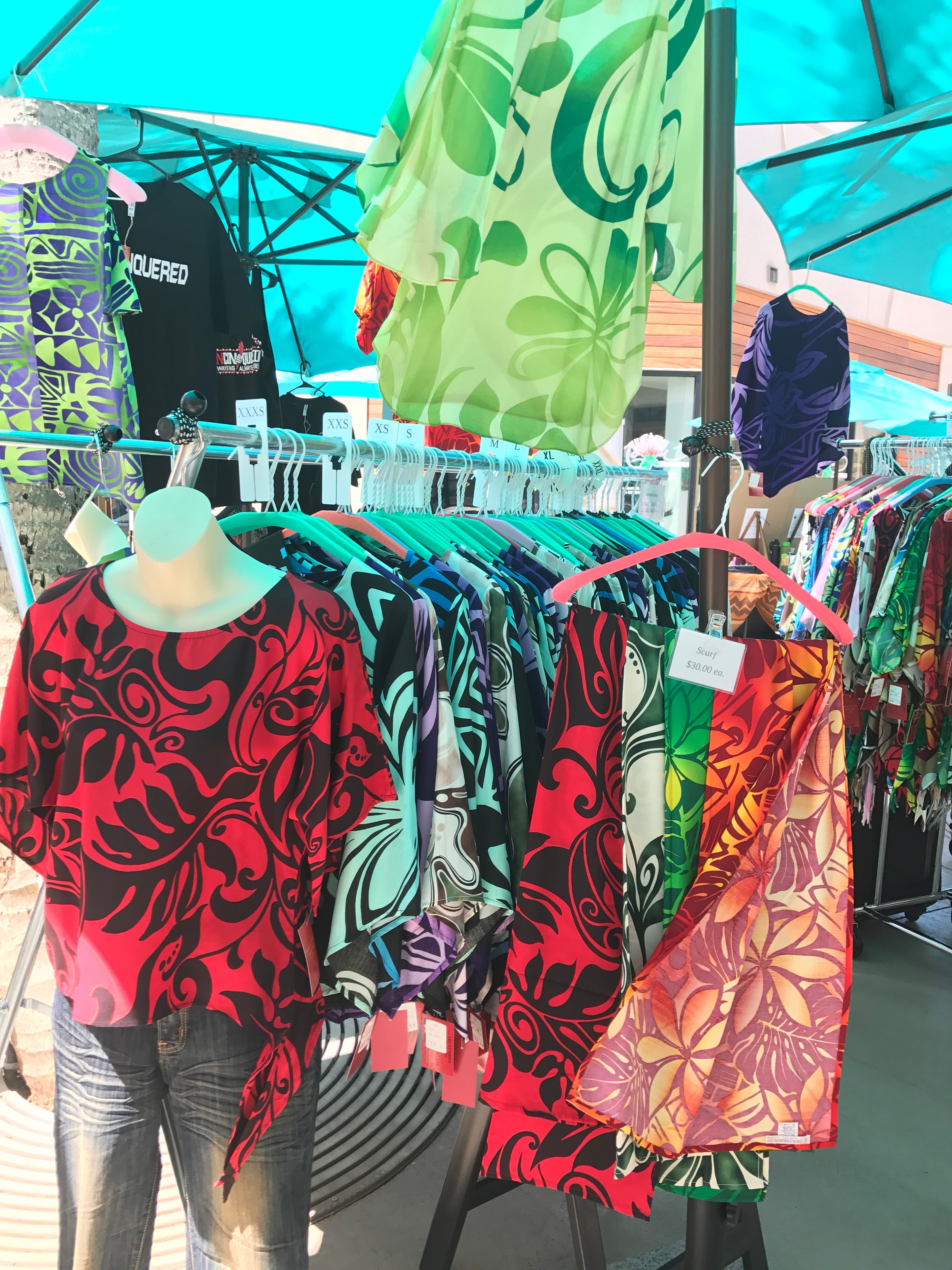 Colorful Hawaiian patterned clothing on rack at outdoor market vendor booth