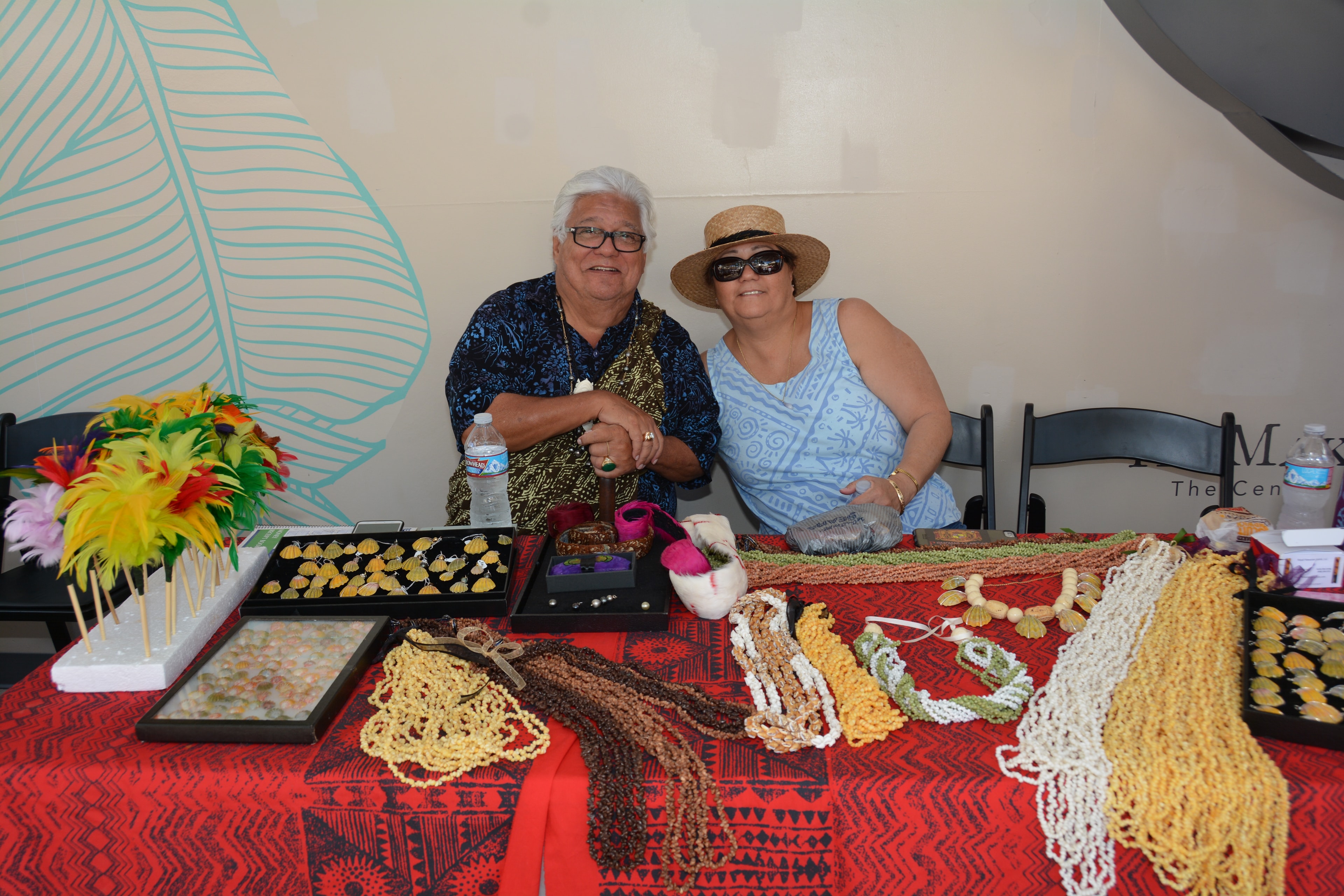 Two people displaying handmade beaded jewelry crafts