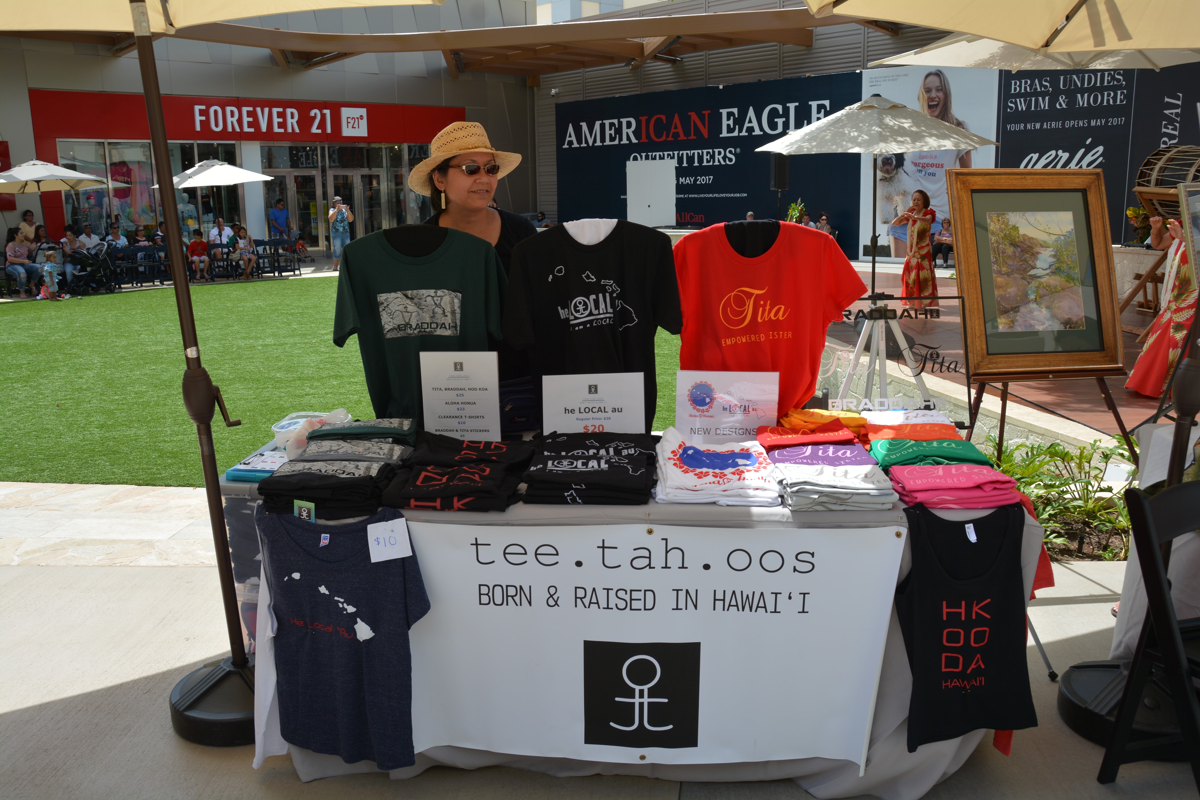 Vendor selling Hawaiian graphic tees outdoor market