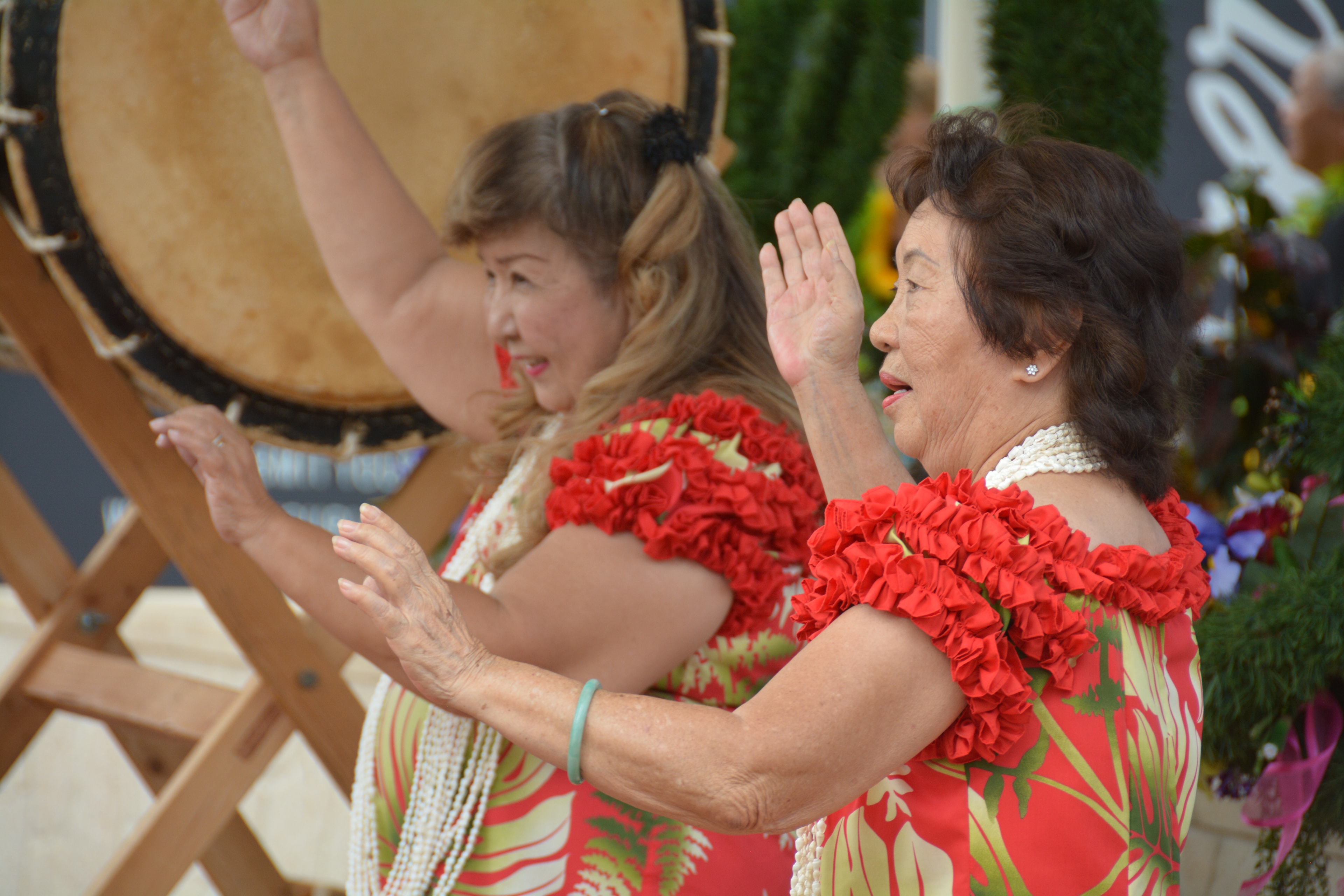 Women playing large drum together outdoors