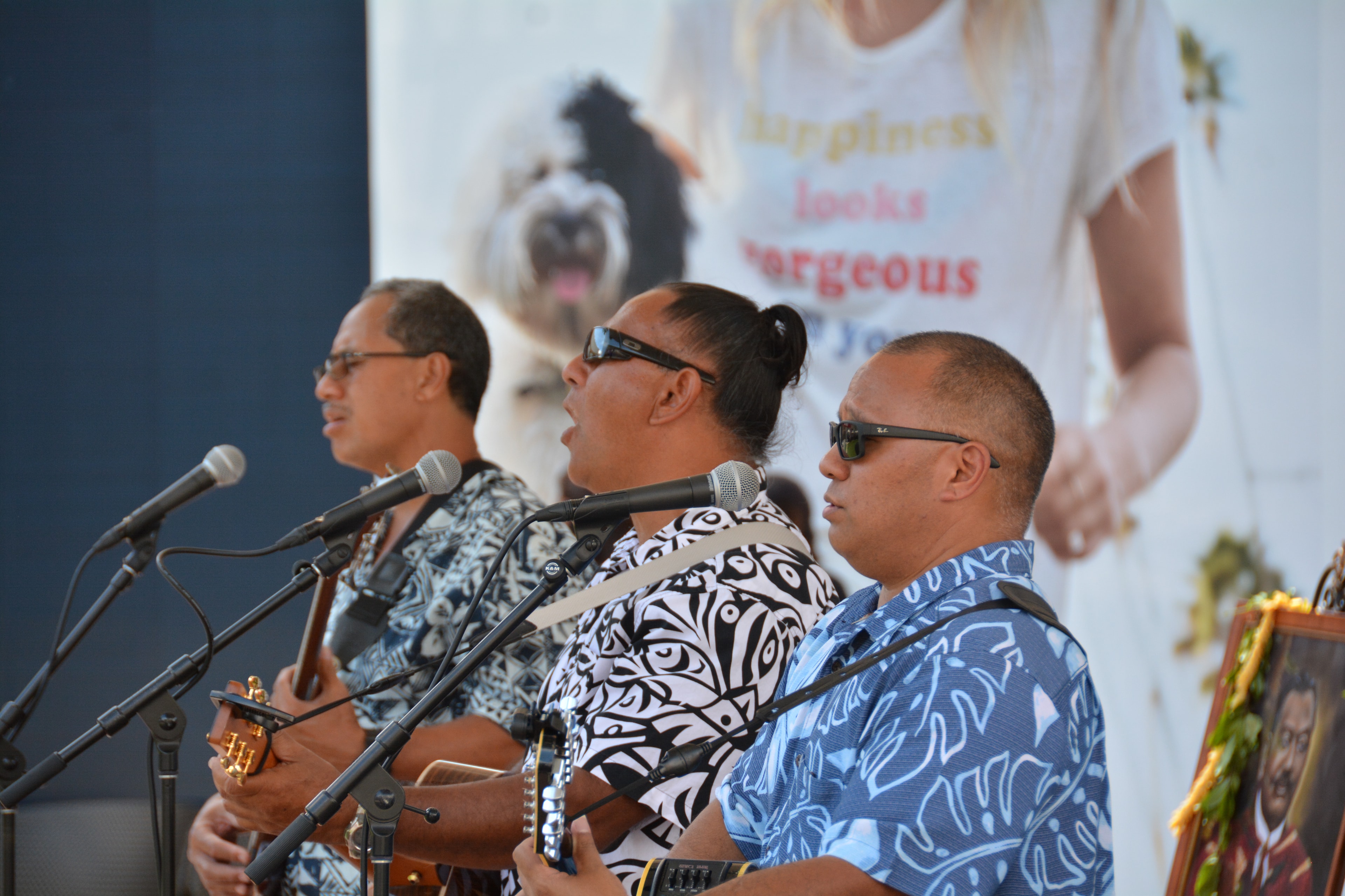 Three men performing with ukuleles on stage
