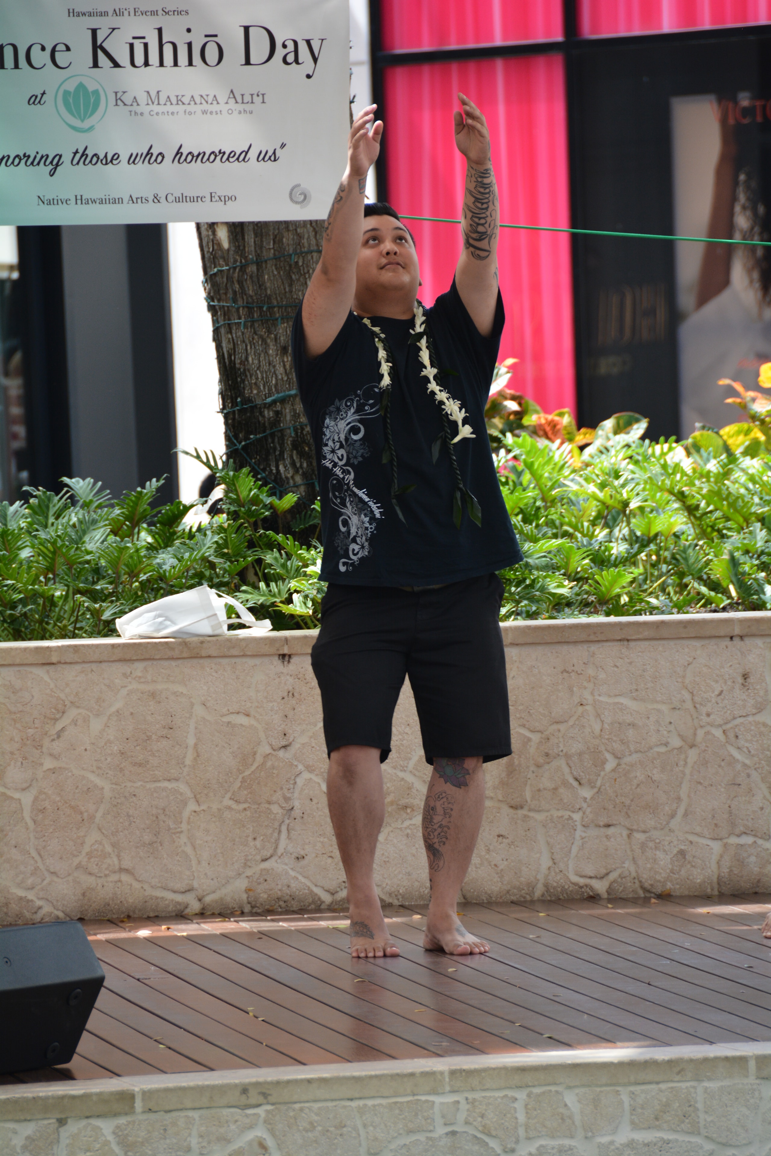 Hawaiian male dancer with arms raised performing at Prince Kūhiō Day