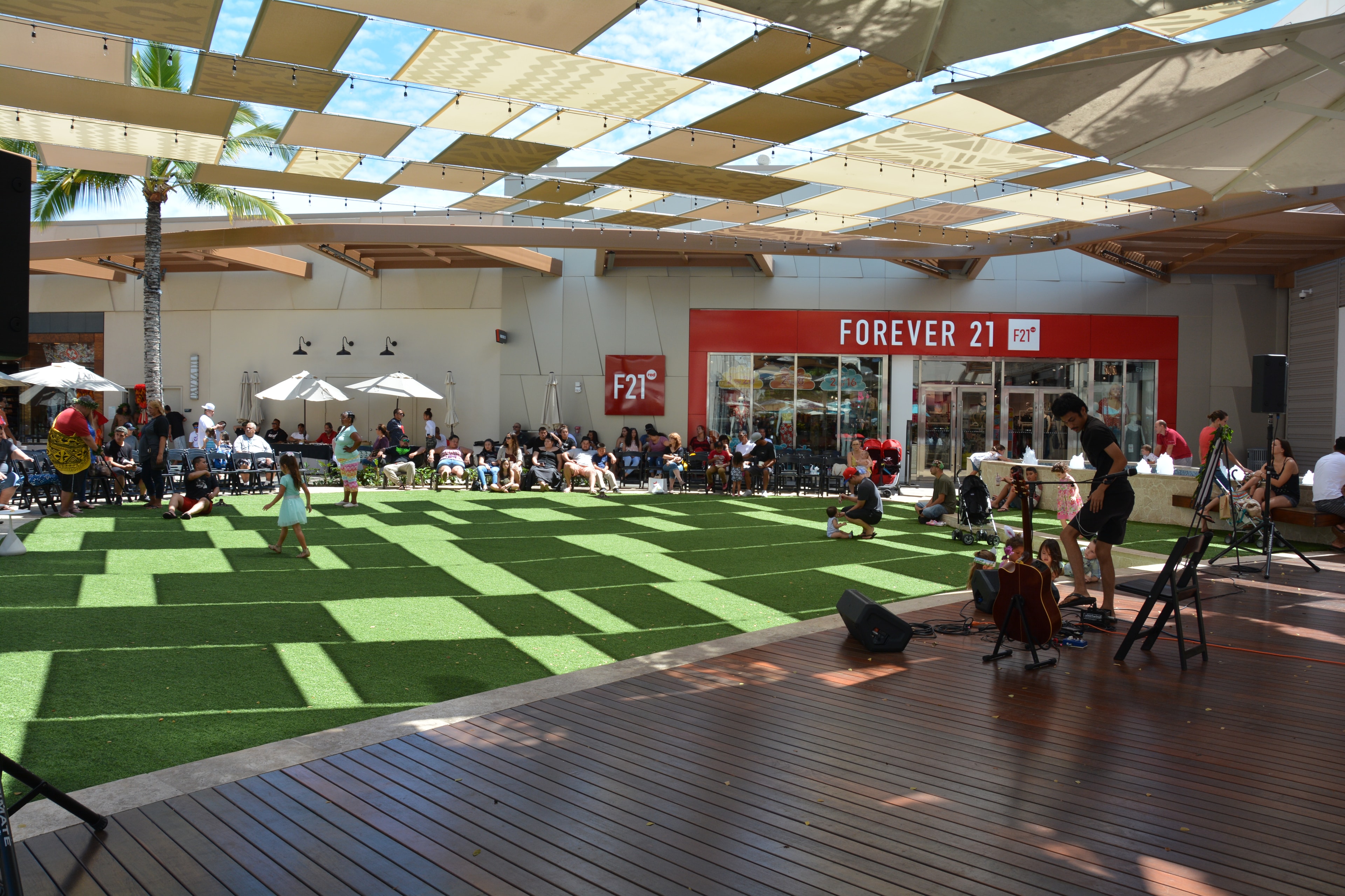 Outdoor event stage at Ka Makana Aliʻi mall with crowd seated on lawn