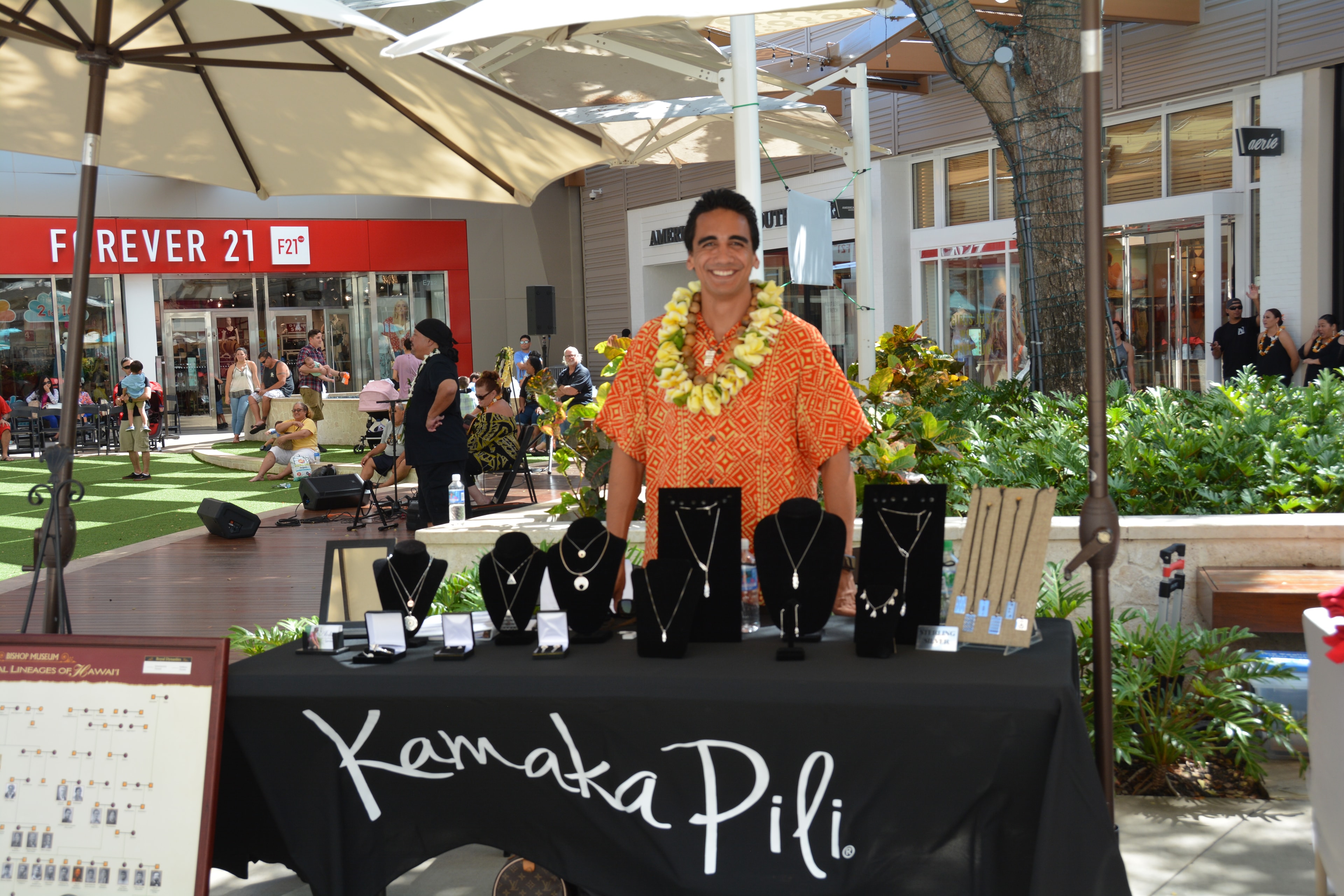 Kamaka Pili jewelry vendor booth with man in orange lei at Ka Makana Aliʻi