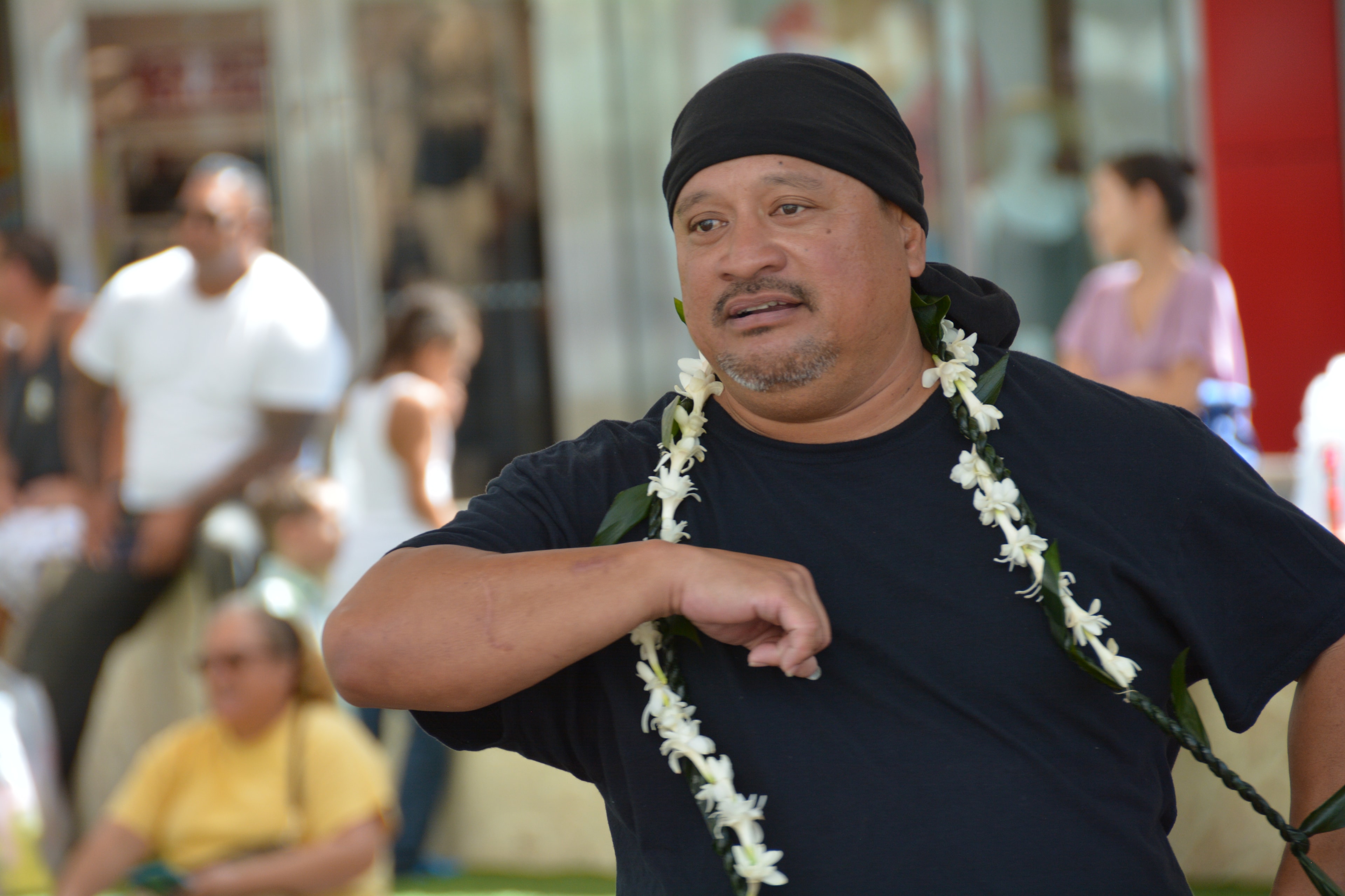 Close-up of Hawaiian male dancer with white lei performing hula at Prince Kūhiō Day