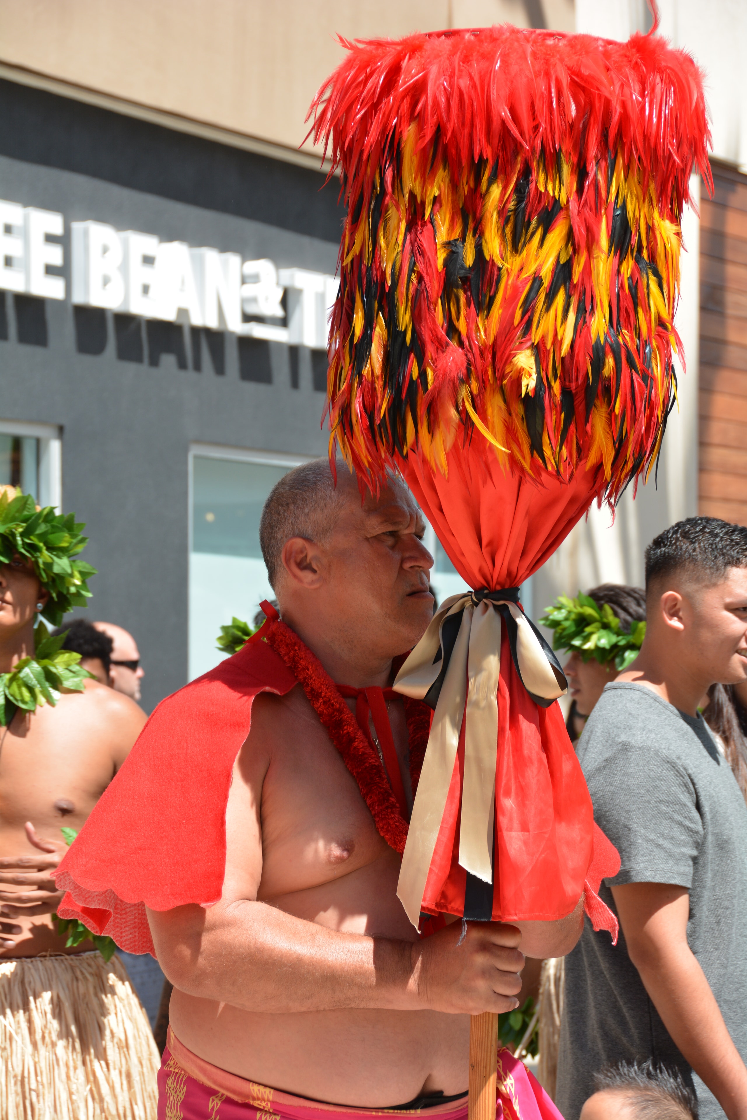 Man wearing flaming red feathered headdress at Prince Kūhiō Day parade
