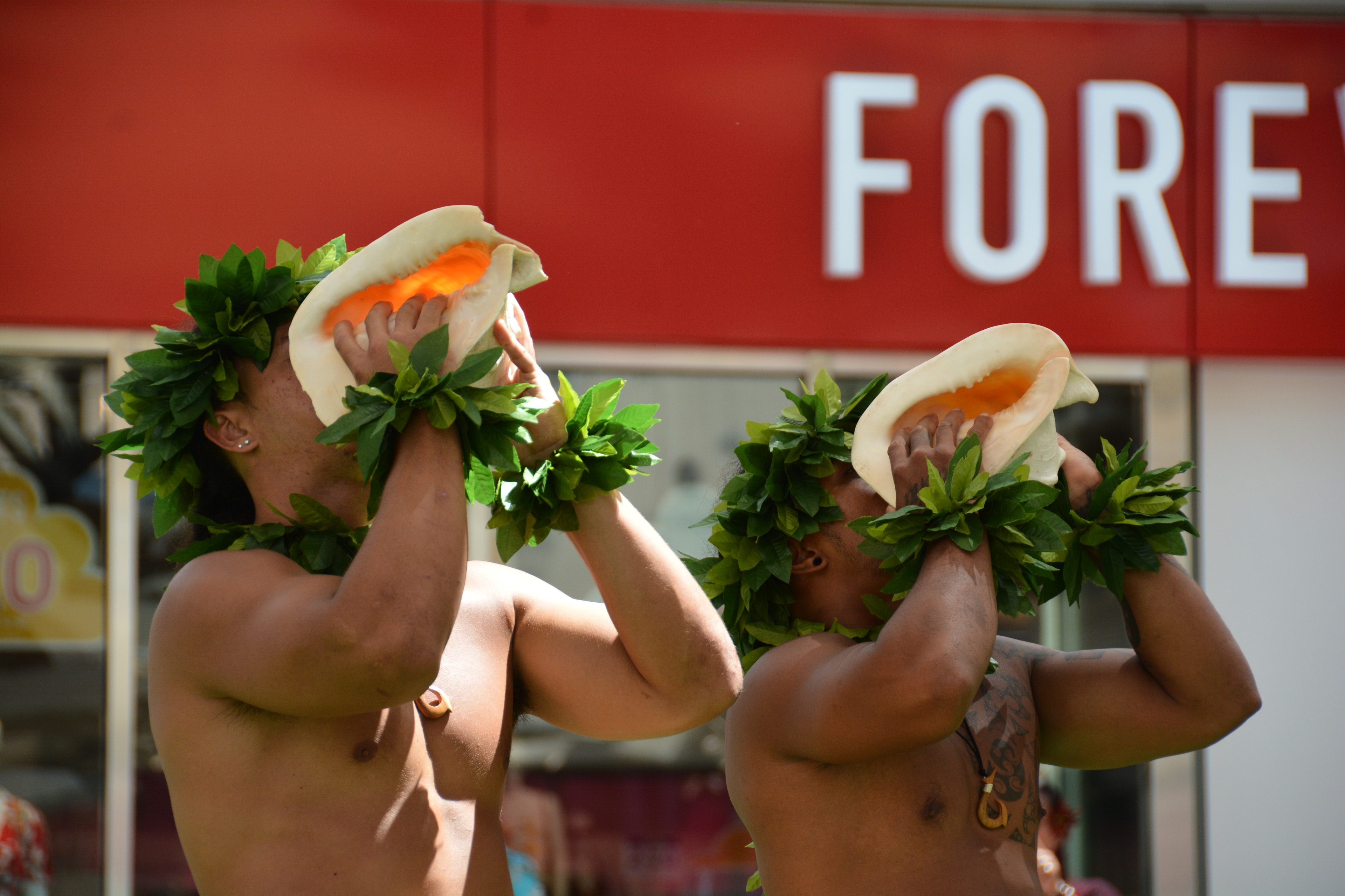 Two performers blowing pū conch shells at Prince Kūhiō Day ceremony