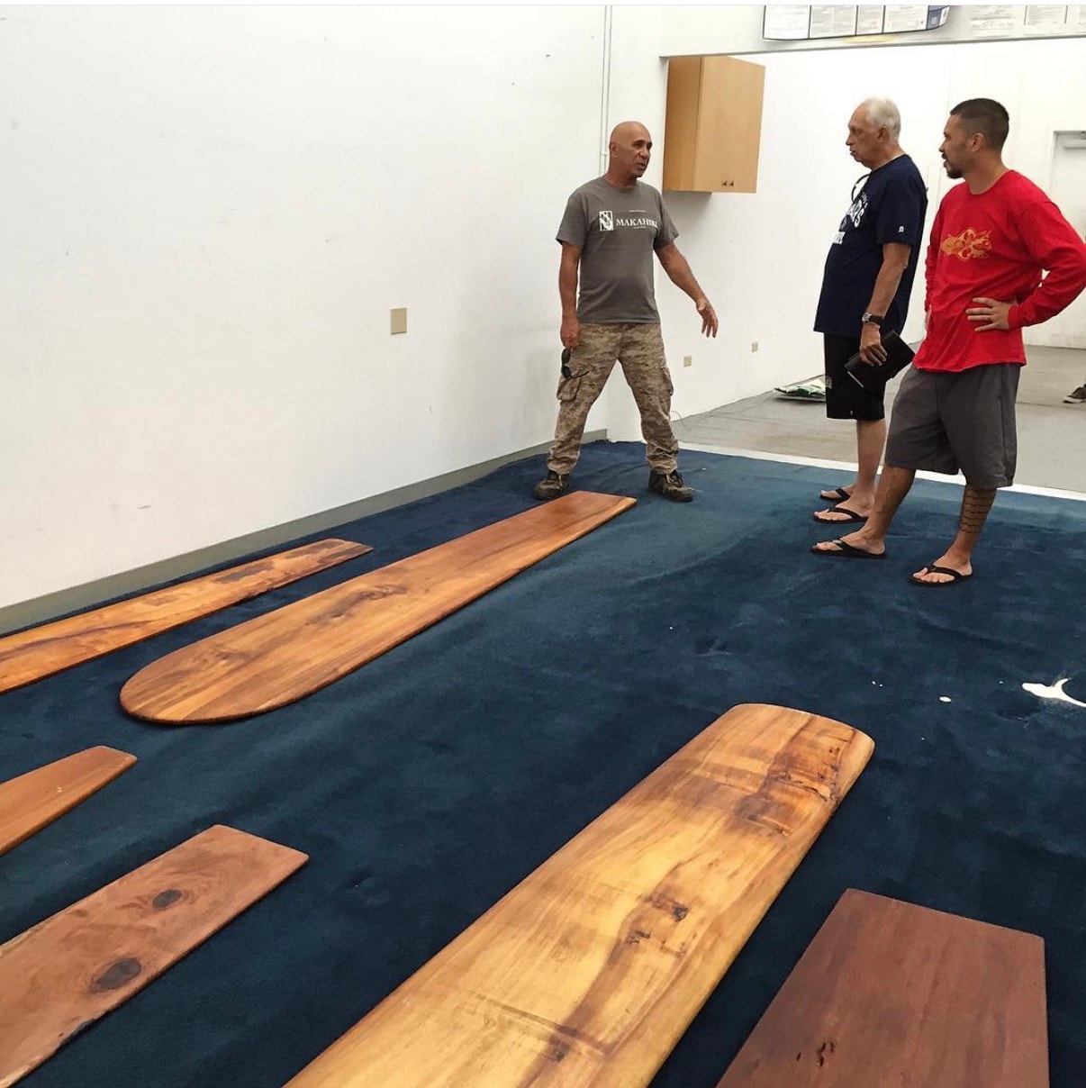 Men discussing wooden surfboards indoors