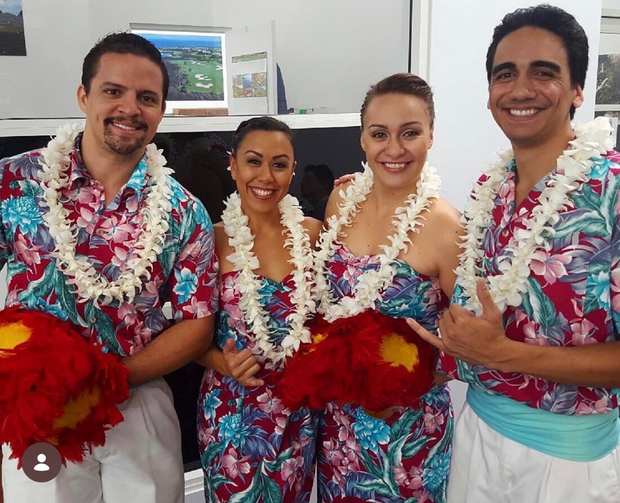 Four people wearing Hawaiian shirts and lei garlands