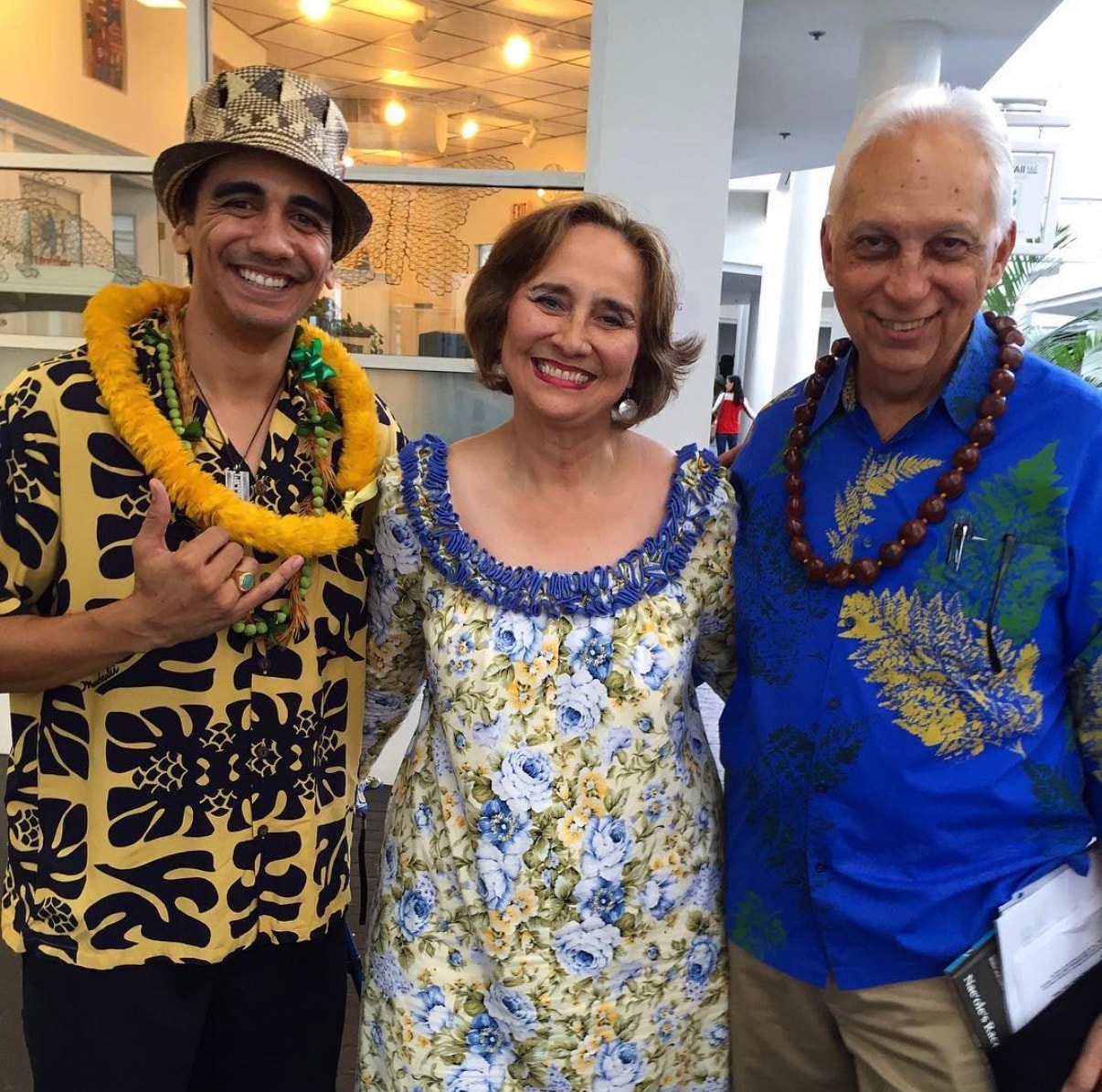 Three people wearing Hawaiian lei and shirts