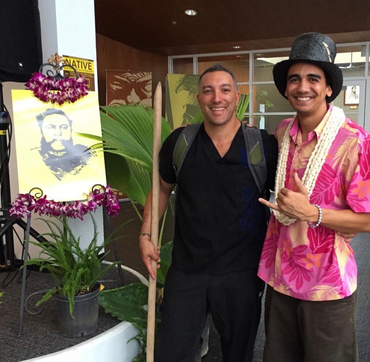 Two men posing with tropical art display