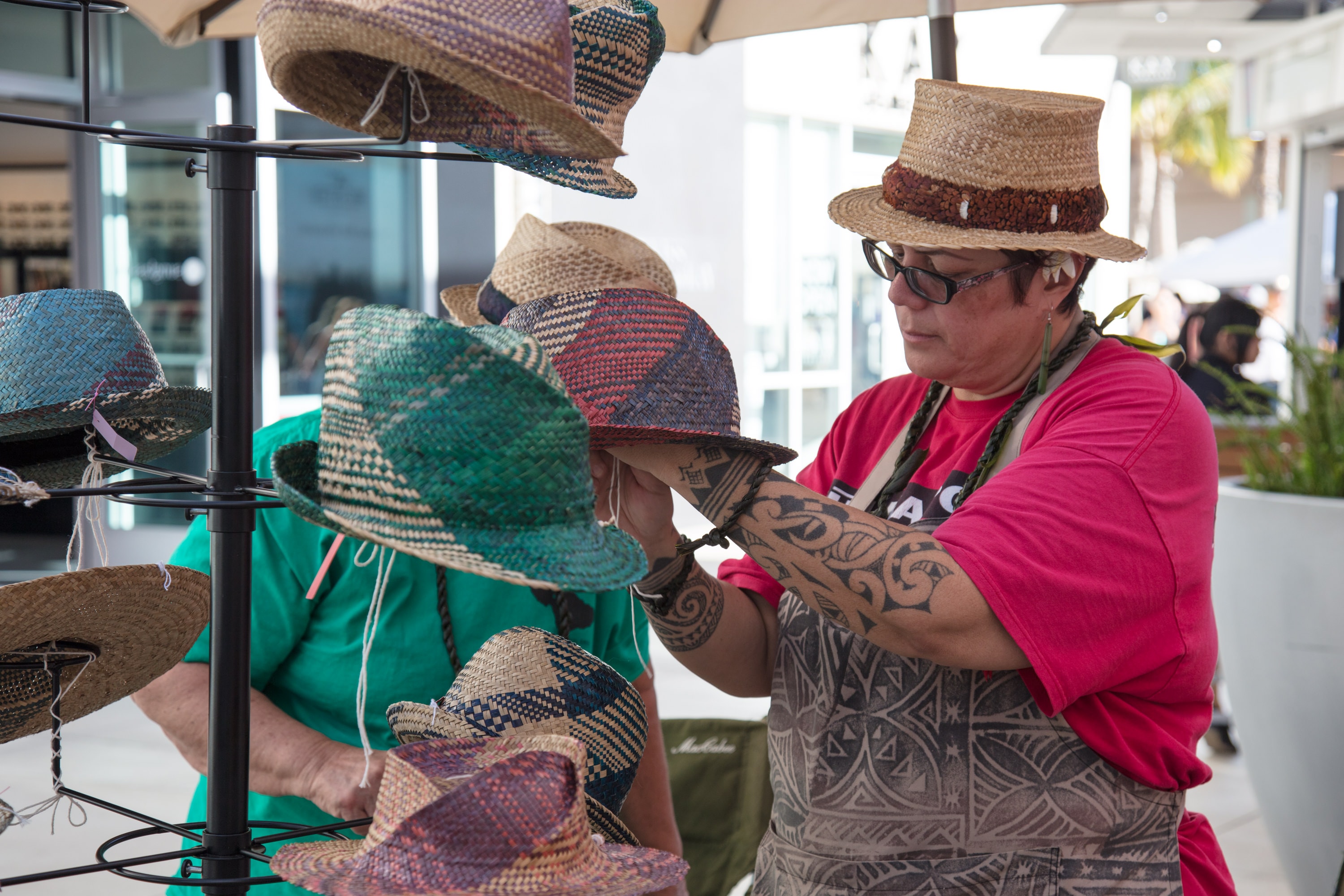 Vendor displaying woven straw hats outdoor market