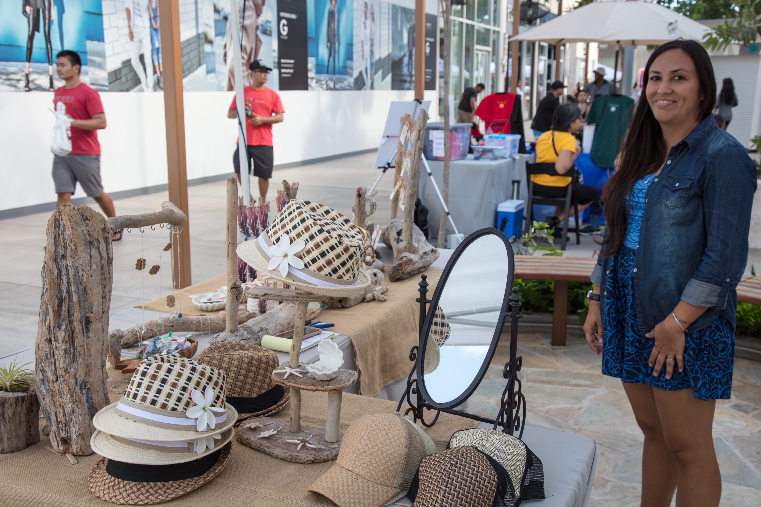 Woman at outdoor market hat display booth