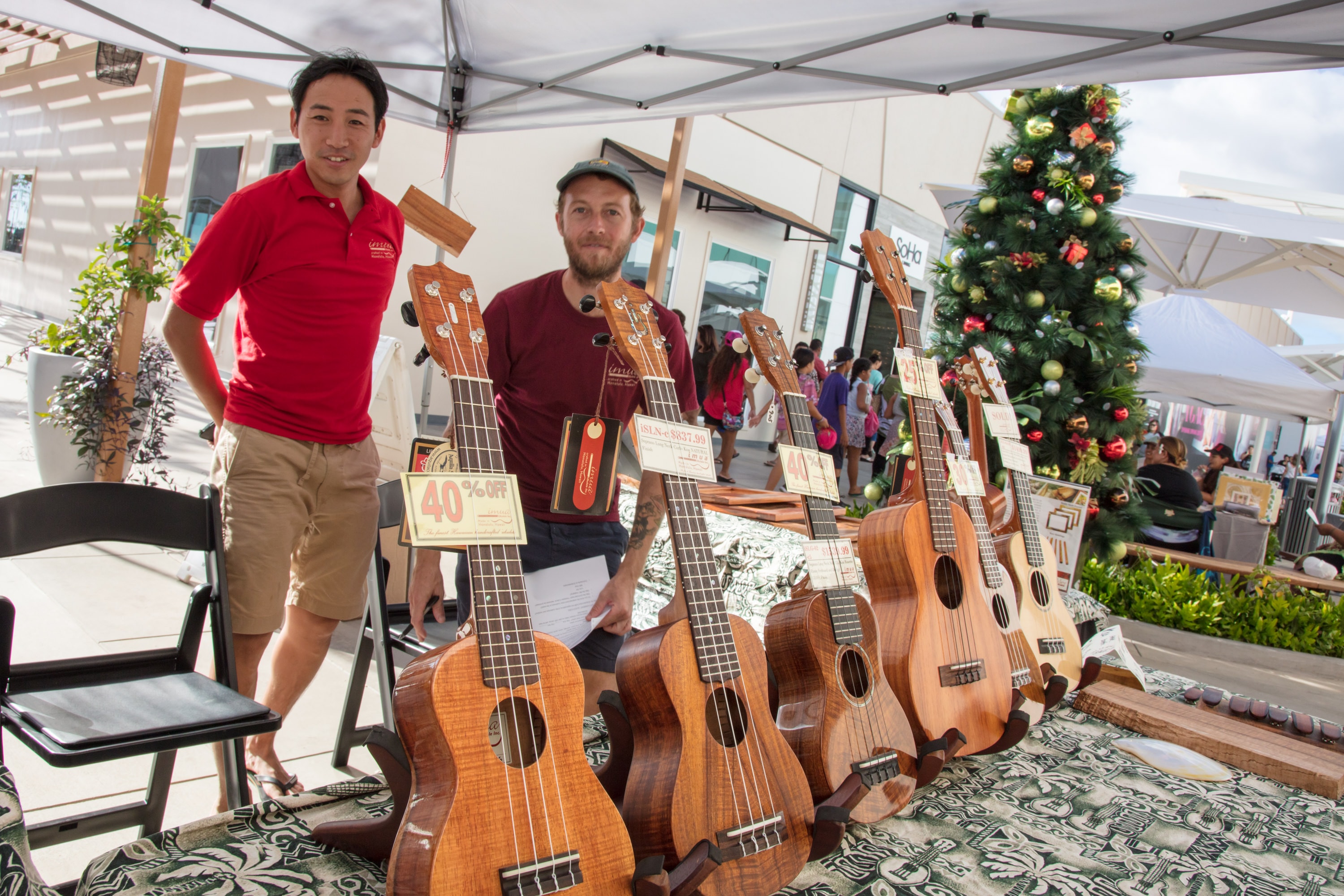 Men selling ukuleles at outdoor market booth