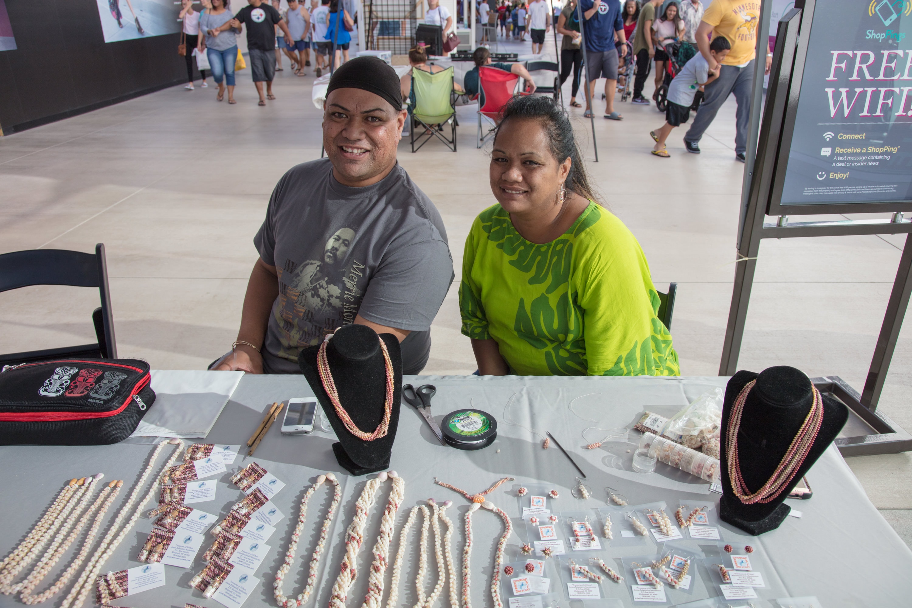 Vendors selling beaded jewelry at market booth