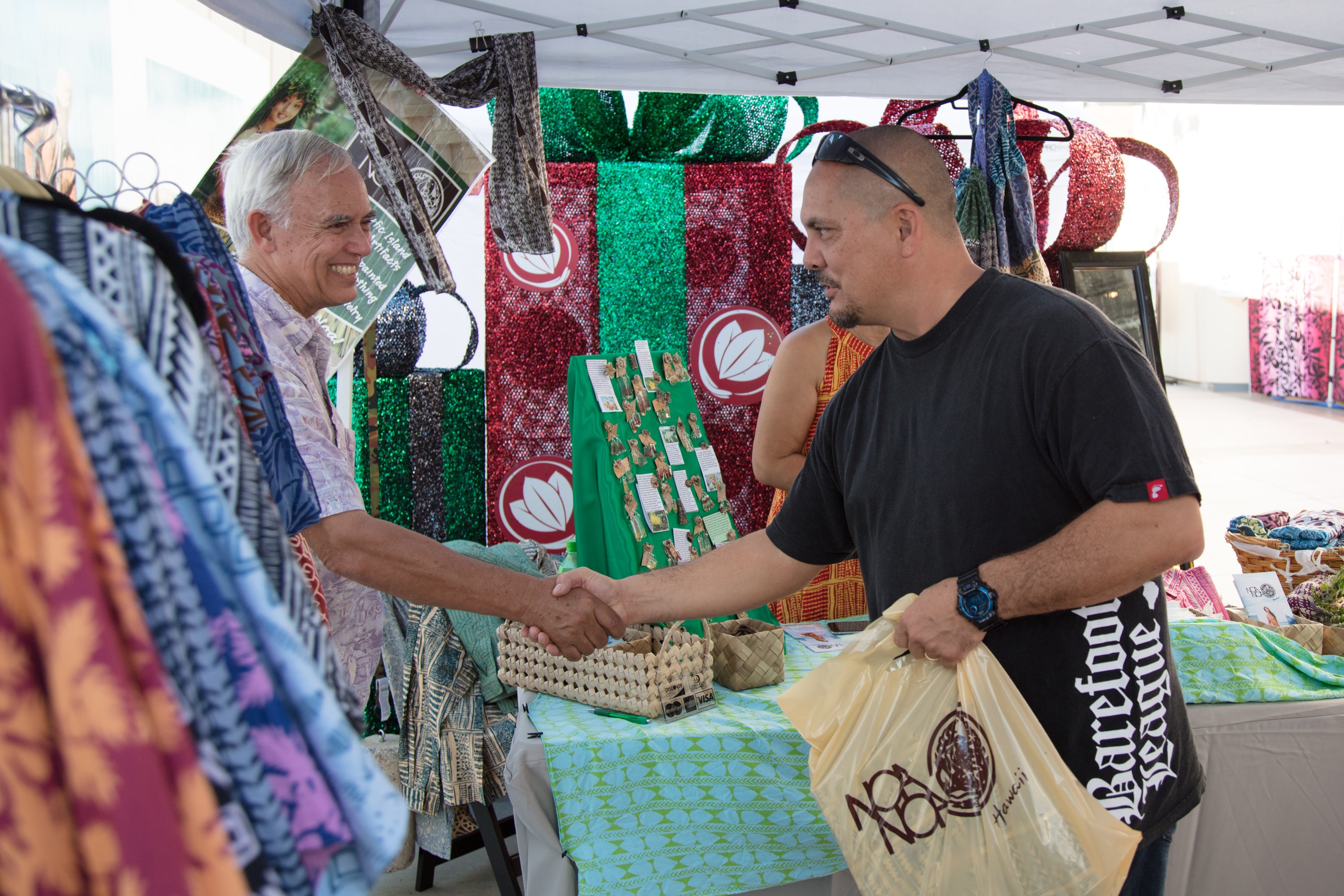Two men shaking hands at craft market booth