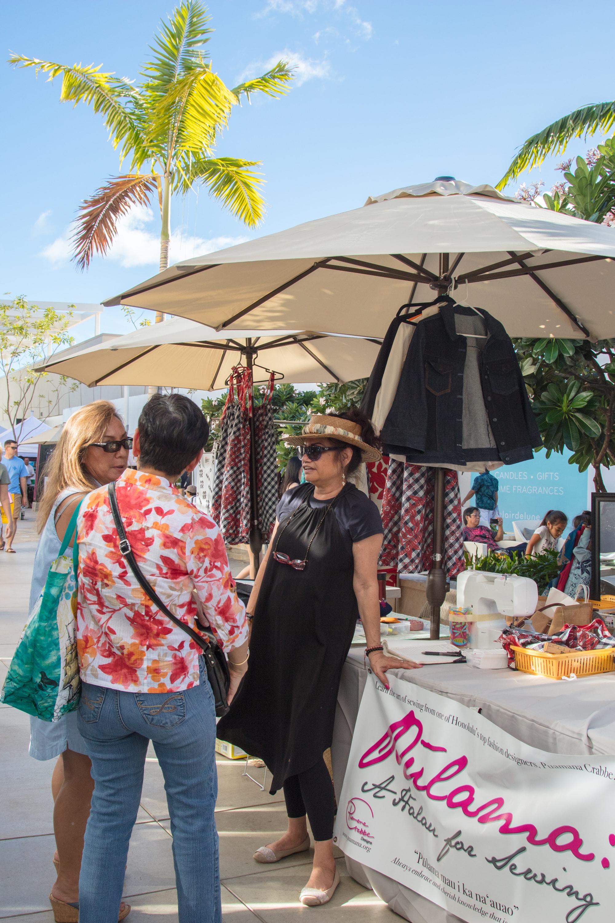 Outdoor market vendor with customers under umbrella