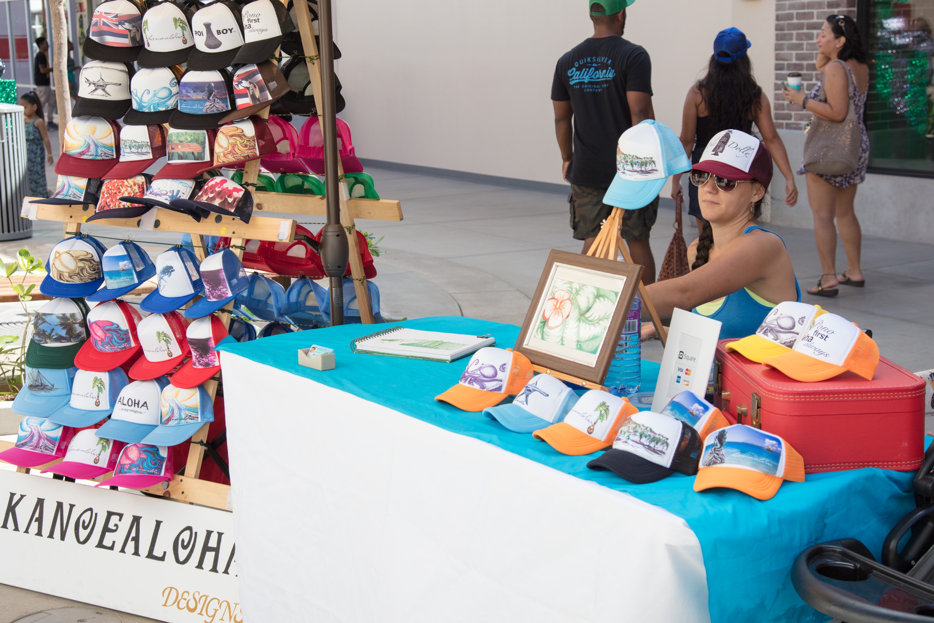 Vendor selling colorful hats at market stall