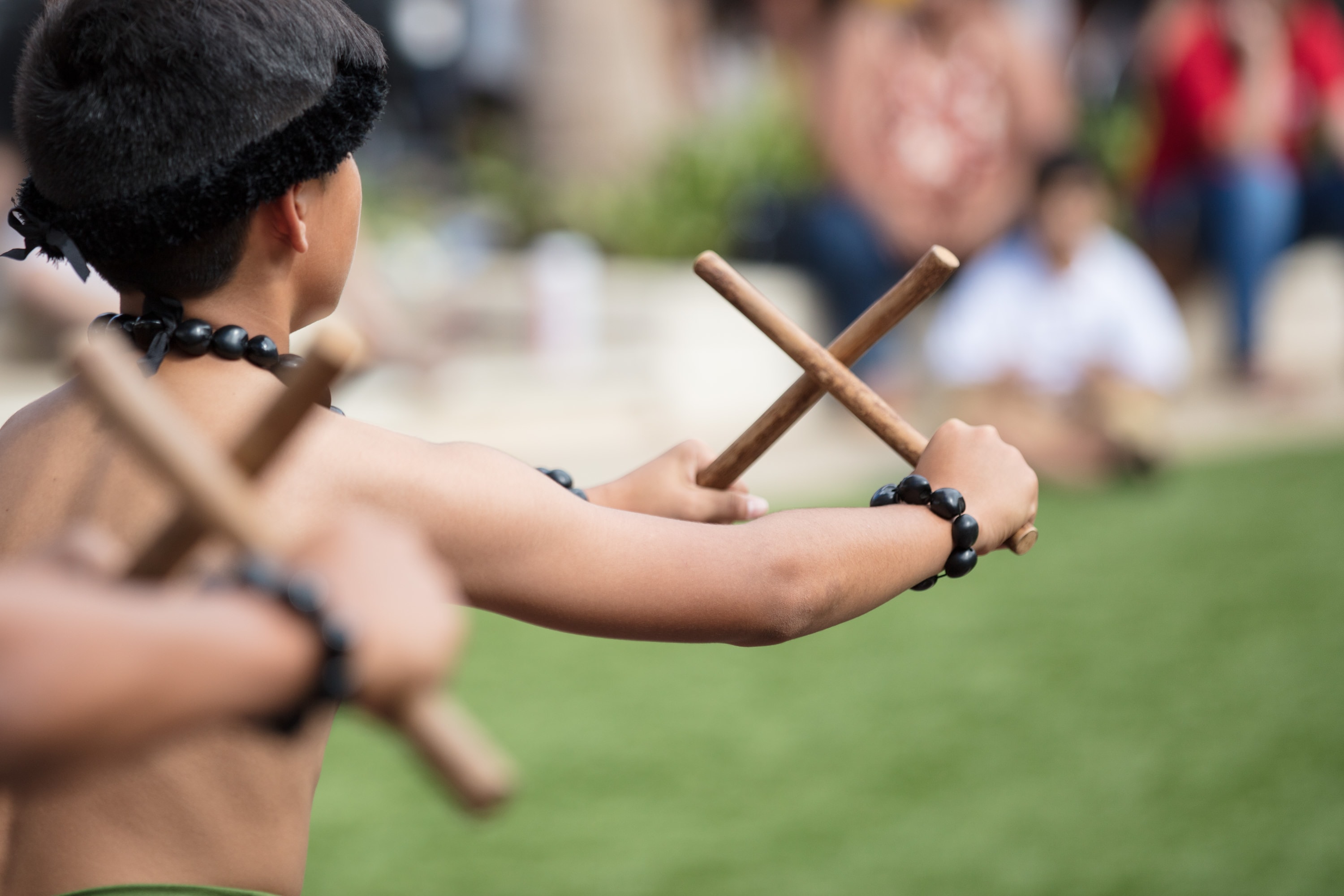 Indigenous child holding wooden sticks outdoors